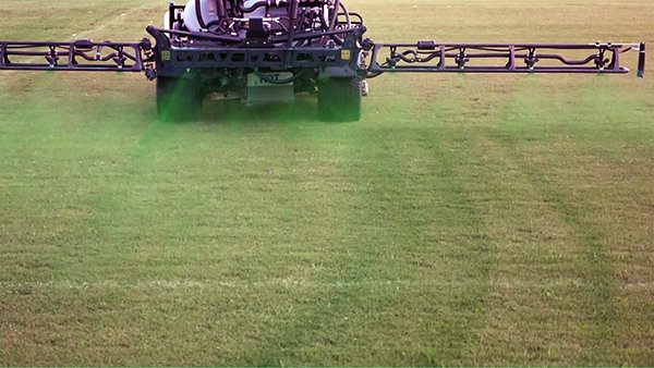 Stripes in bermudagrass sports field due to spray drift from an 11 mile-per-hour headwind affecting boom spray